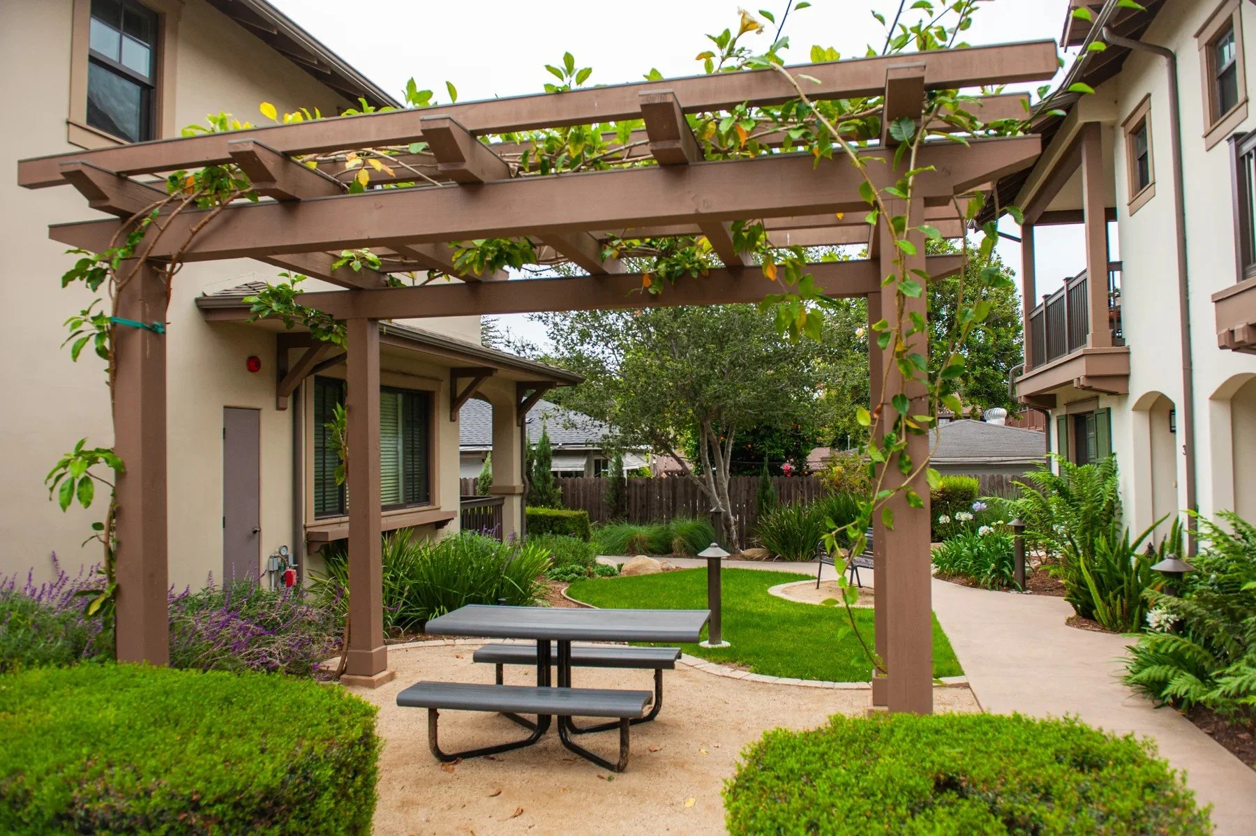 A trellis-covered table and shared courtyard garden at Tejado Grove