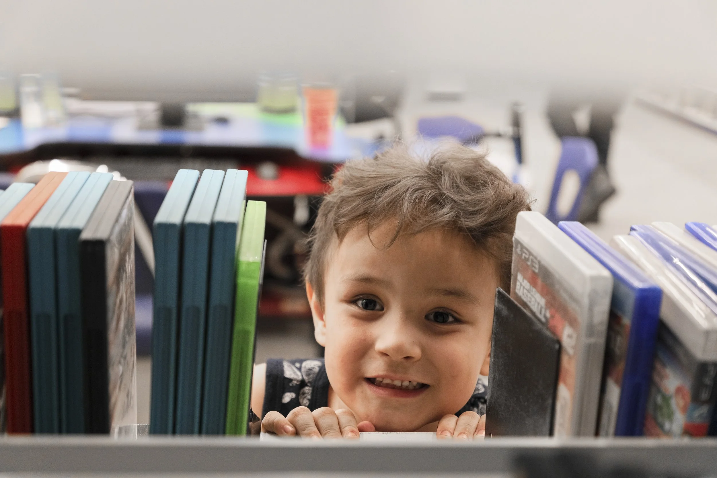 Child reading between rows of books