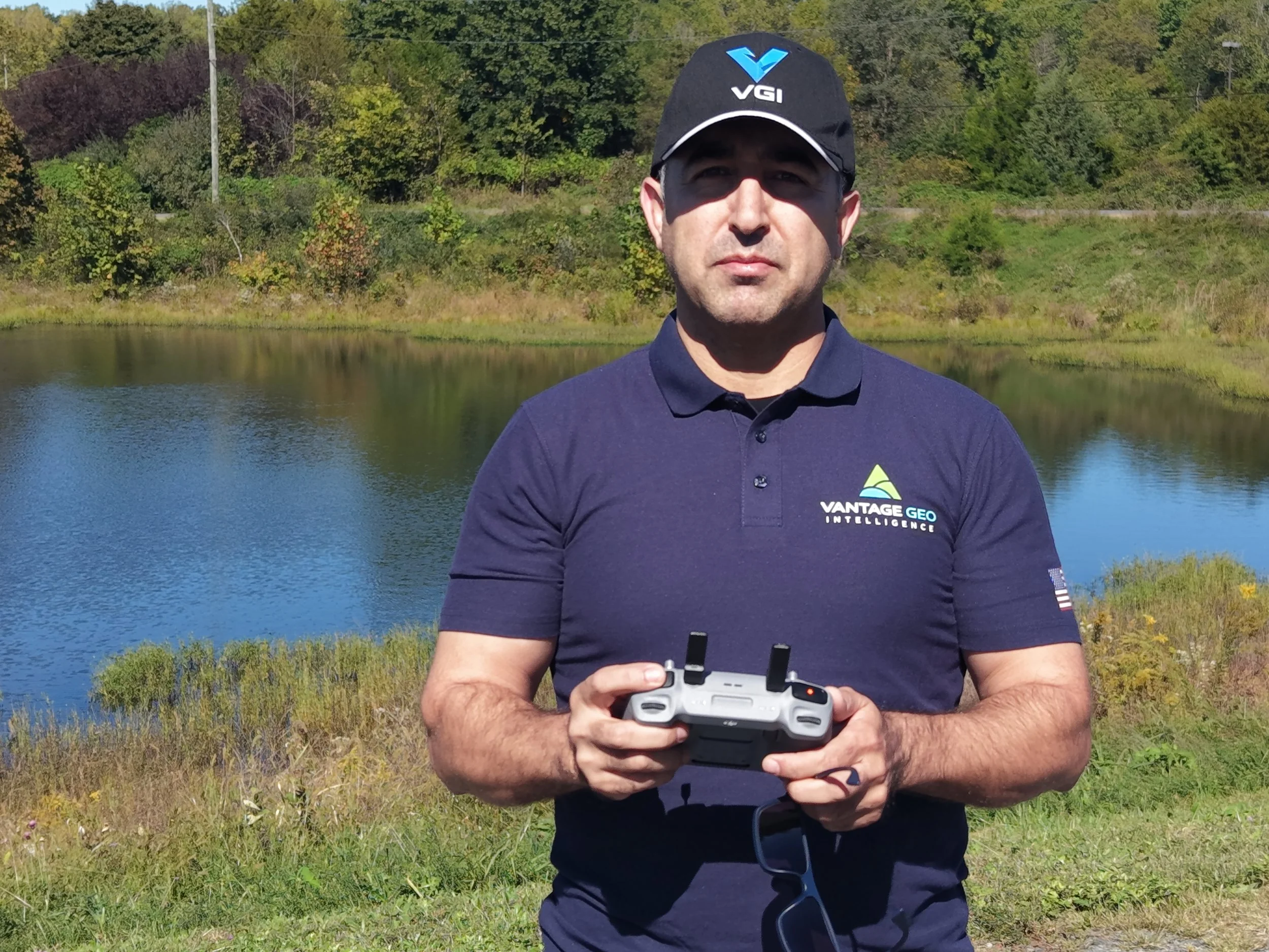 Sayd Hopiane, founder and CEO of Vantage Geo Intelligence, holding a drone controller beside a lake