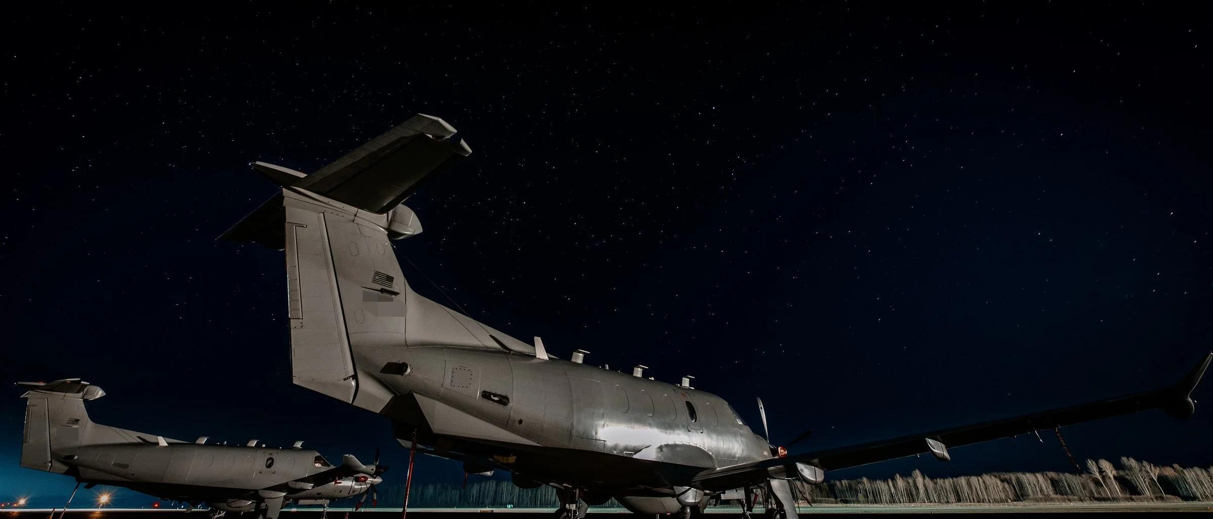 Two special-operations aircraft on a runway under a starry sky