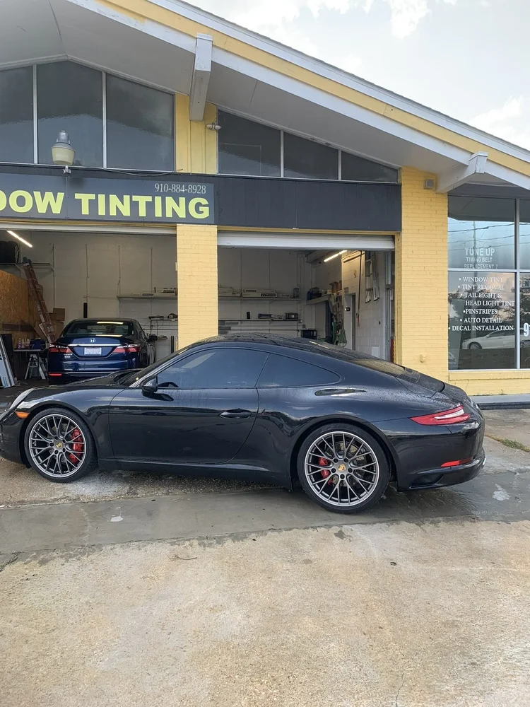 Black Porsche 911 with tinted windows in front of the Perfect Shade shop