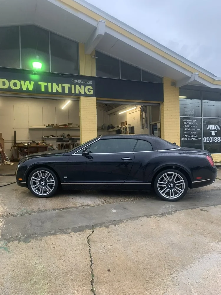 Dark Bentley Continental GT with tinted windows outside the shop