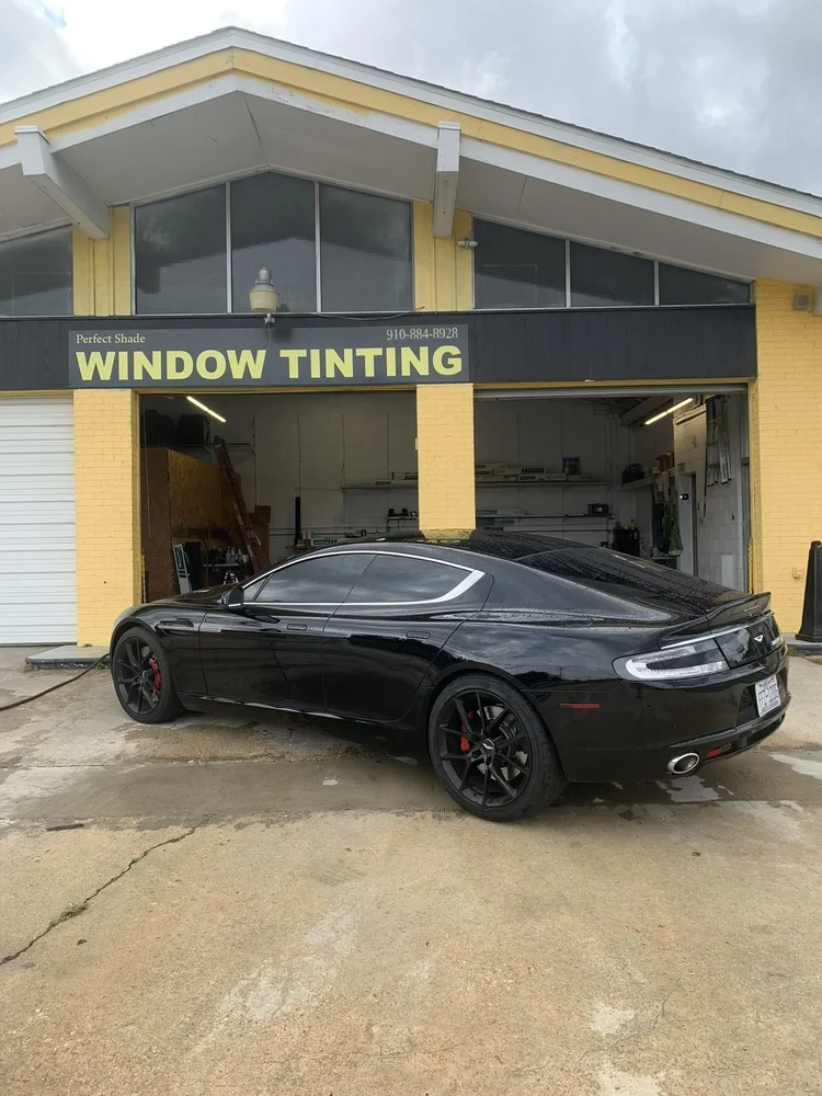 Black Aston Martin with tinted windows outside Perfect Shade