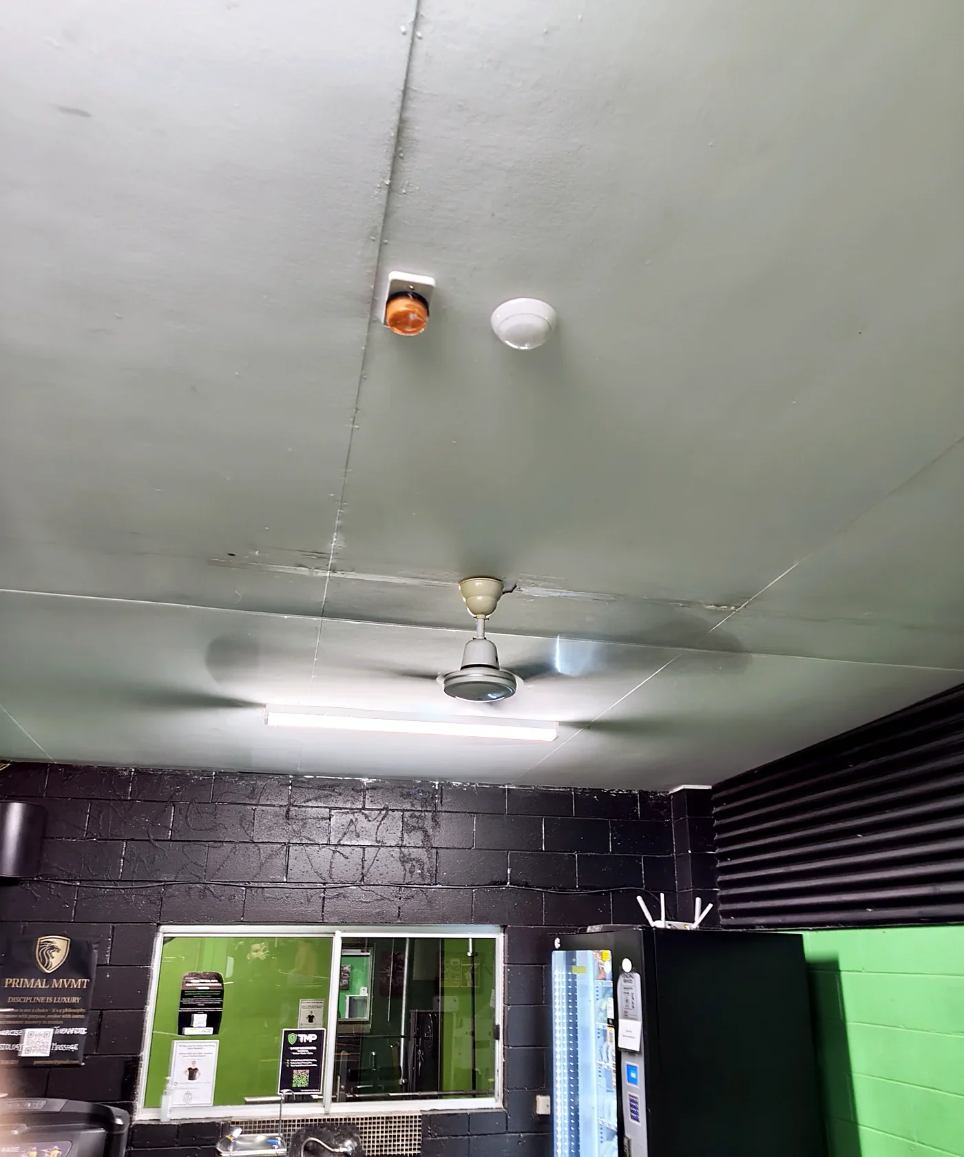 Before: an old white ceiling fan on a grey ceiling in a gym