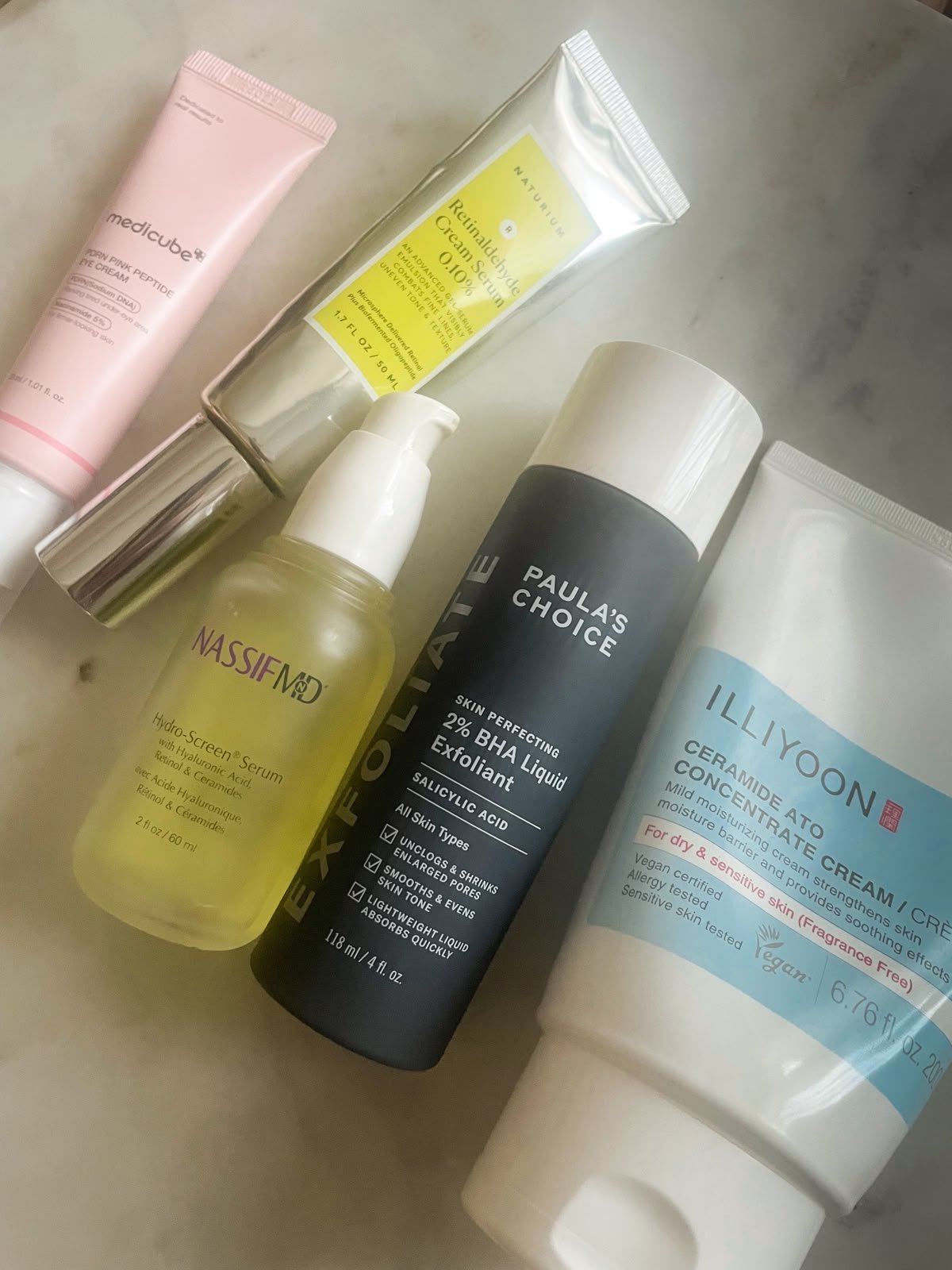 Skincare routine products on marble — Paula's Choice, NassifMD, Illiyoon, Naturium, Medicube