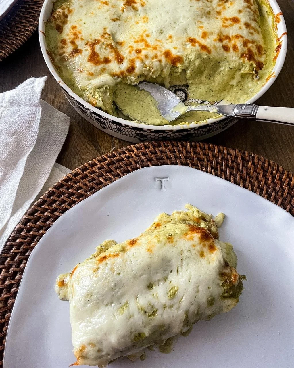 Plated enchiladas suizas with melted Monterrey cheese on a white plate