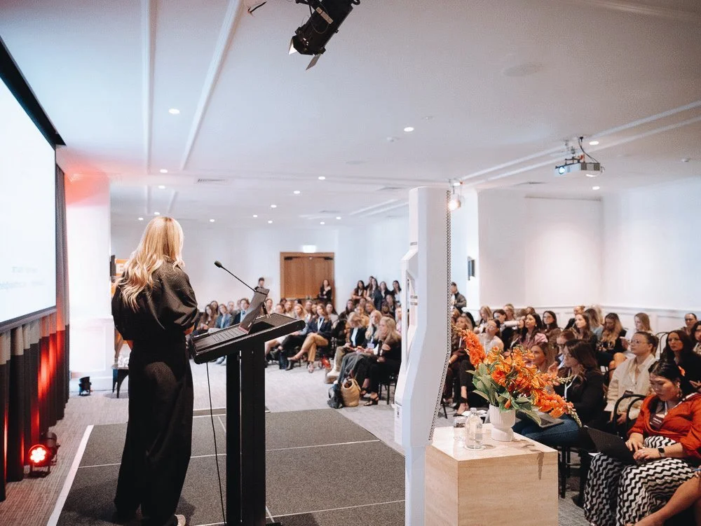 Britt speaking to a full room at a keynote