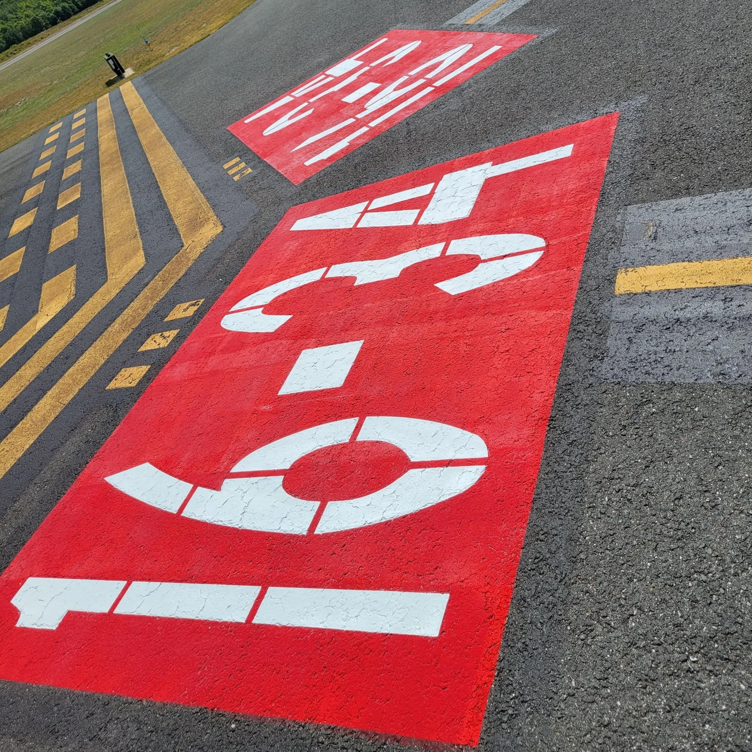 Airport runway or taxiway pavement markings painted in high-visibility colors by Infinity Line Co.