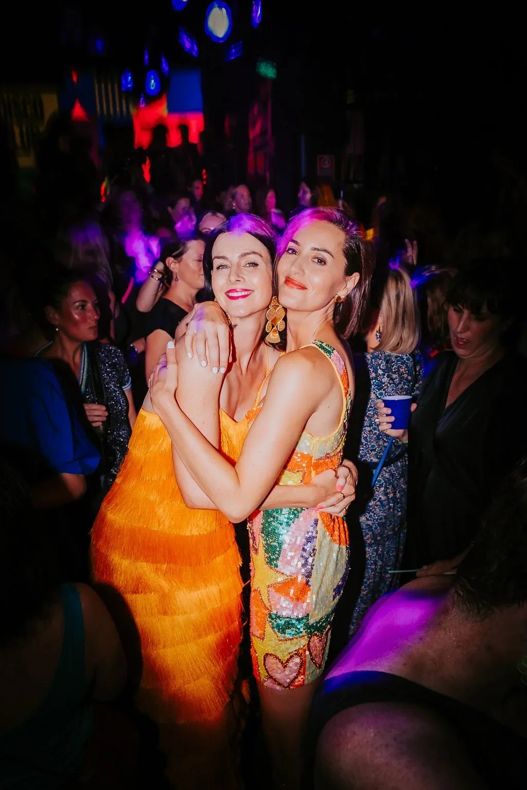 Lise and Sarah hugging on a crowded DISCO CLUB dance floor