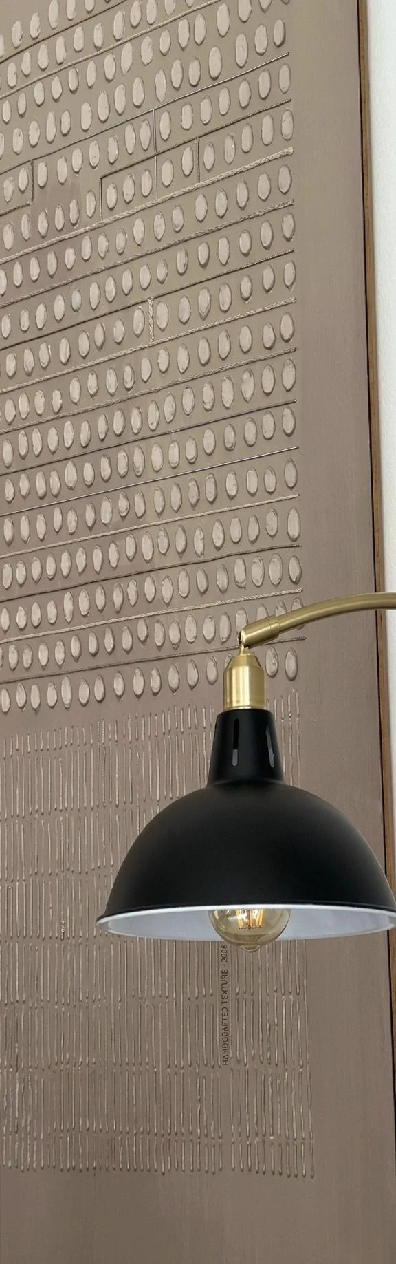 Large-scale textured wall art with a sleek brass floor lamp