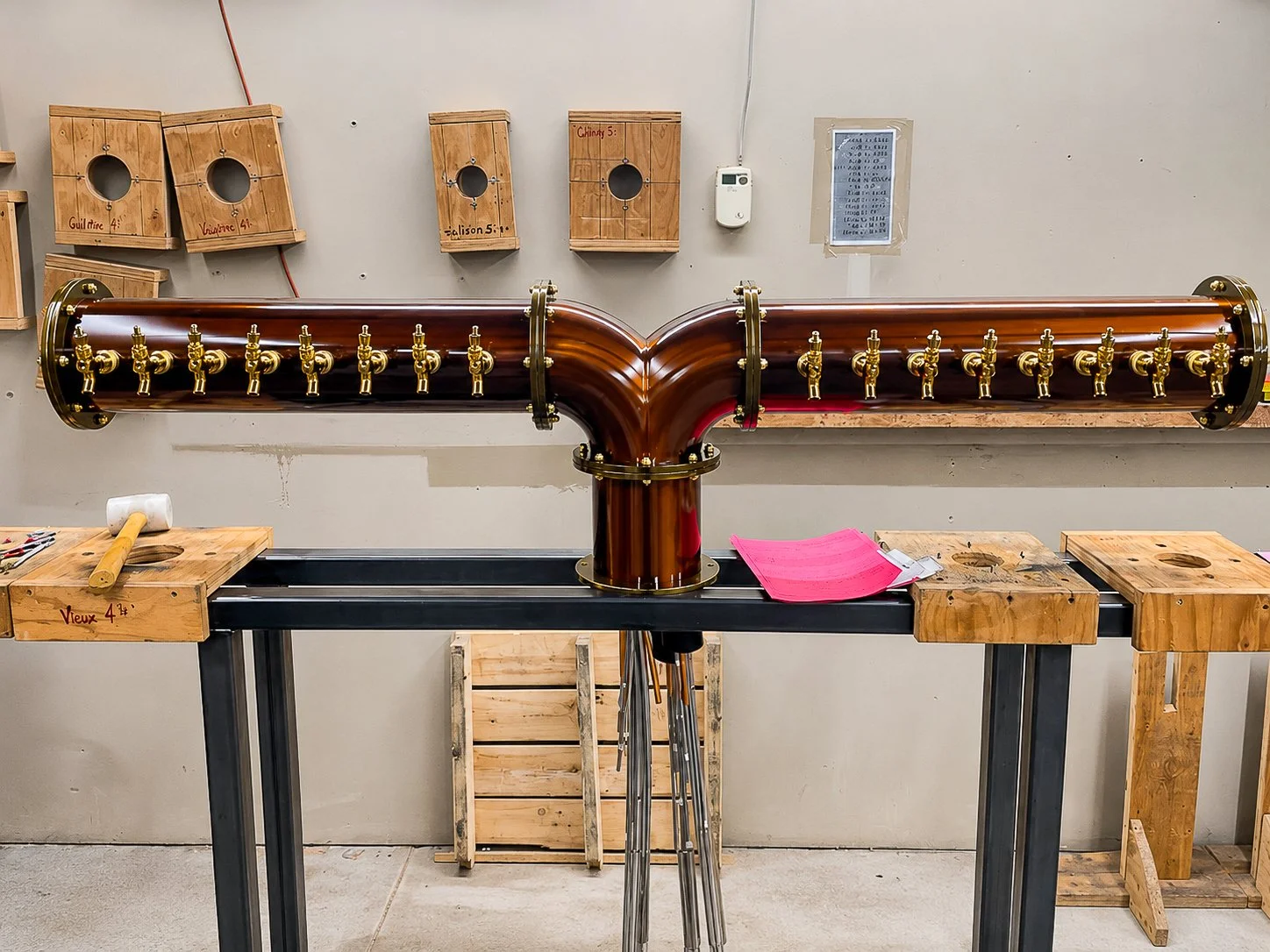 Front view of the completed custom draft tower with two rows of polished brass taps on its central copper column.