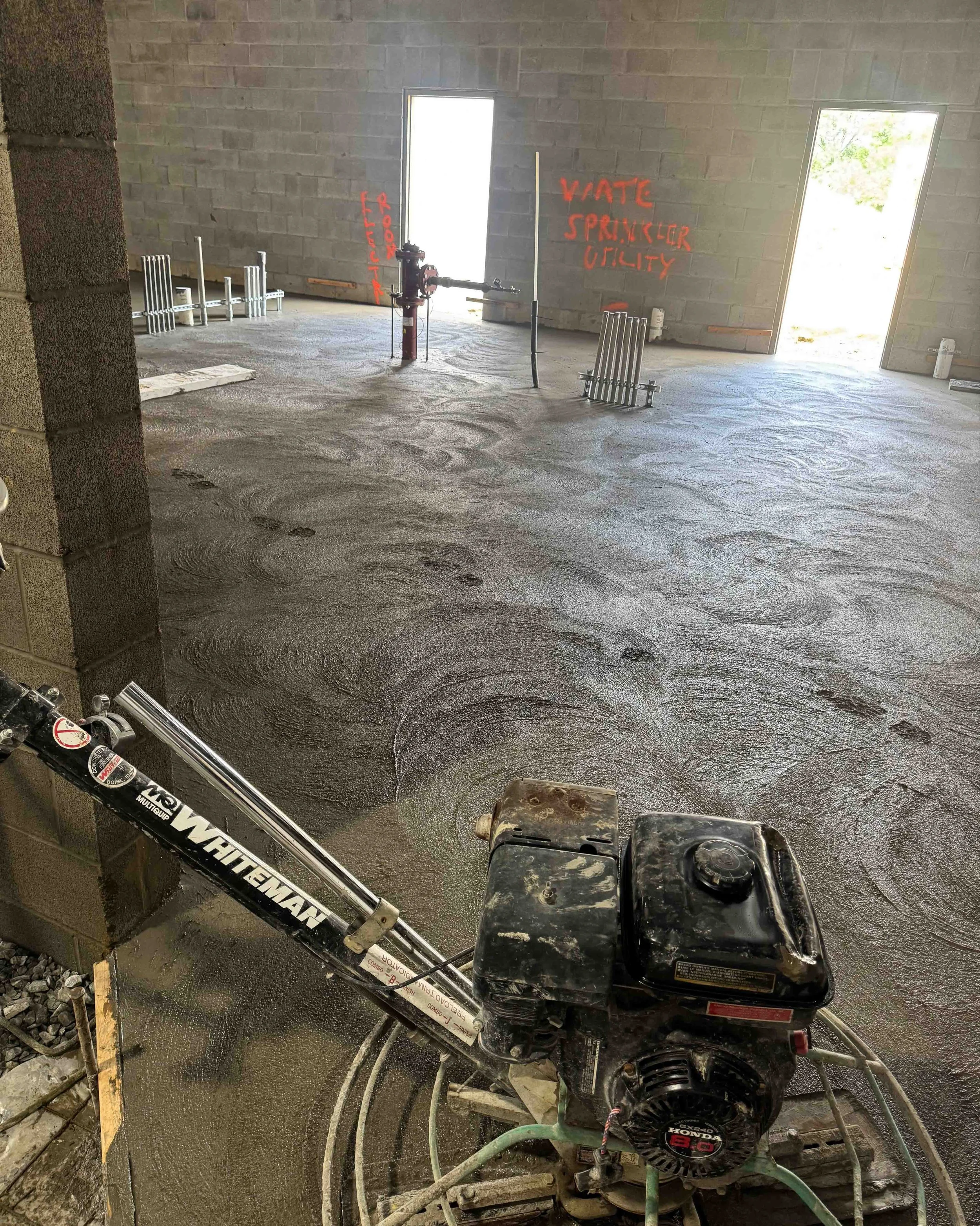 Freshly poured concrete slab being machine-floated with a walk-behind power trowel during construction at Common Ground Kitchen & Taps in McMurray, PA.