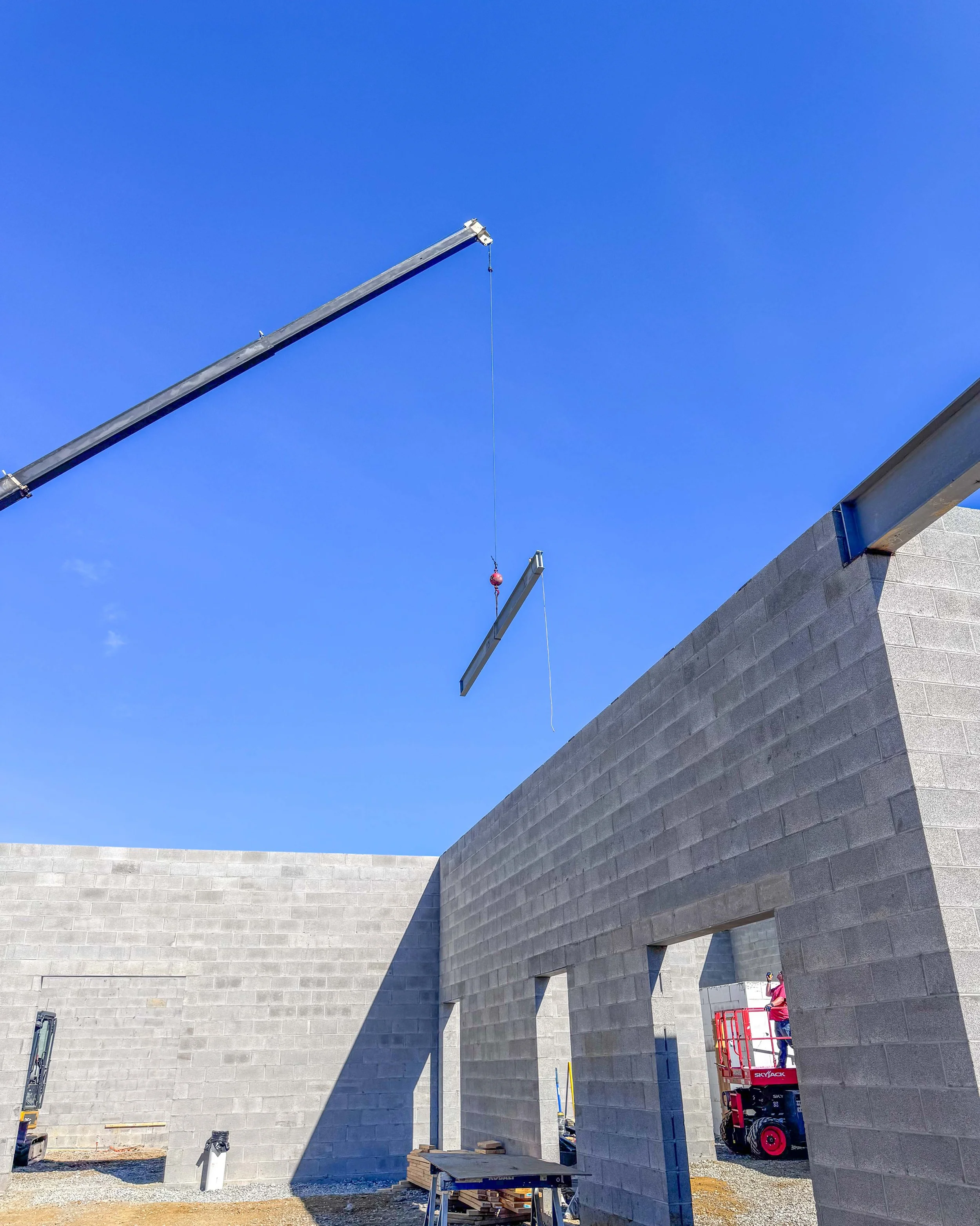 Crane lifting a steel beam above the concrete block walls of Common Ground Kitchen & Taps in McMurray, PA.