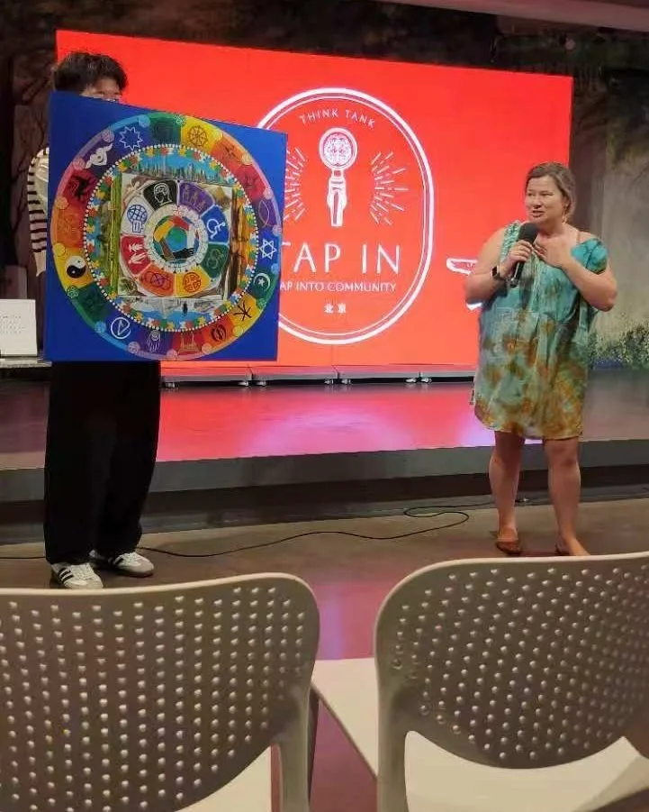 Janice Stewart-Yates speaking beside a colourful DEI mandala painting at a Tap In event
