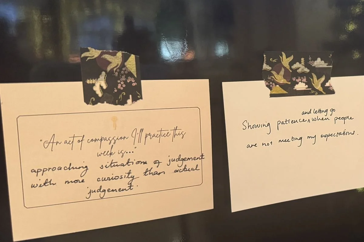 Handwritten cards on a Commitment Wall reading: an act of compassion I'll practice this week is approaching judgement with more curiosity