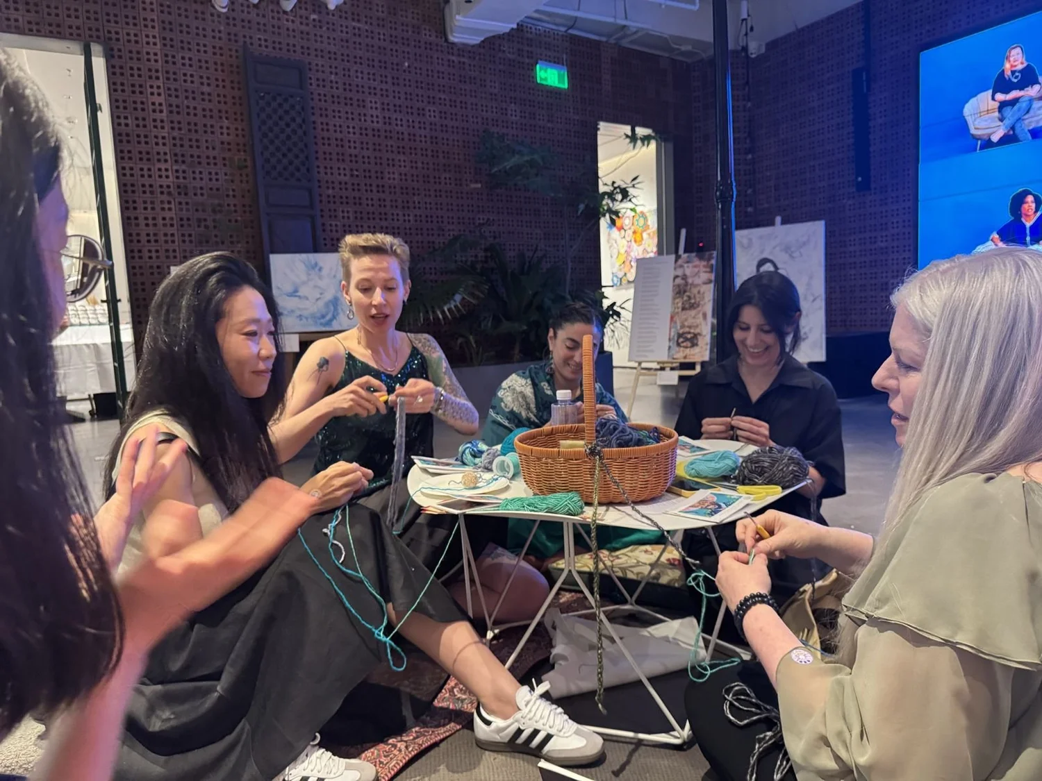 Visitors sitting together in a crochet circle at Voices of Light