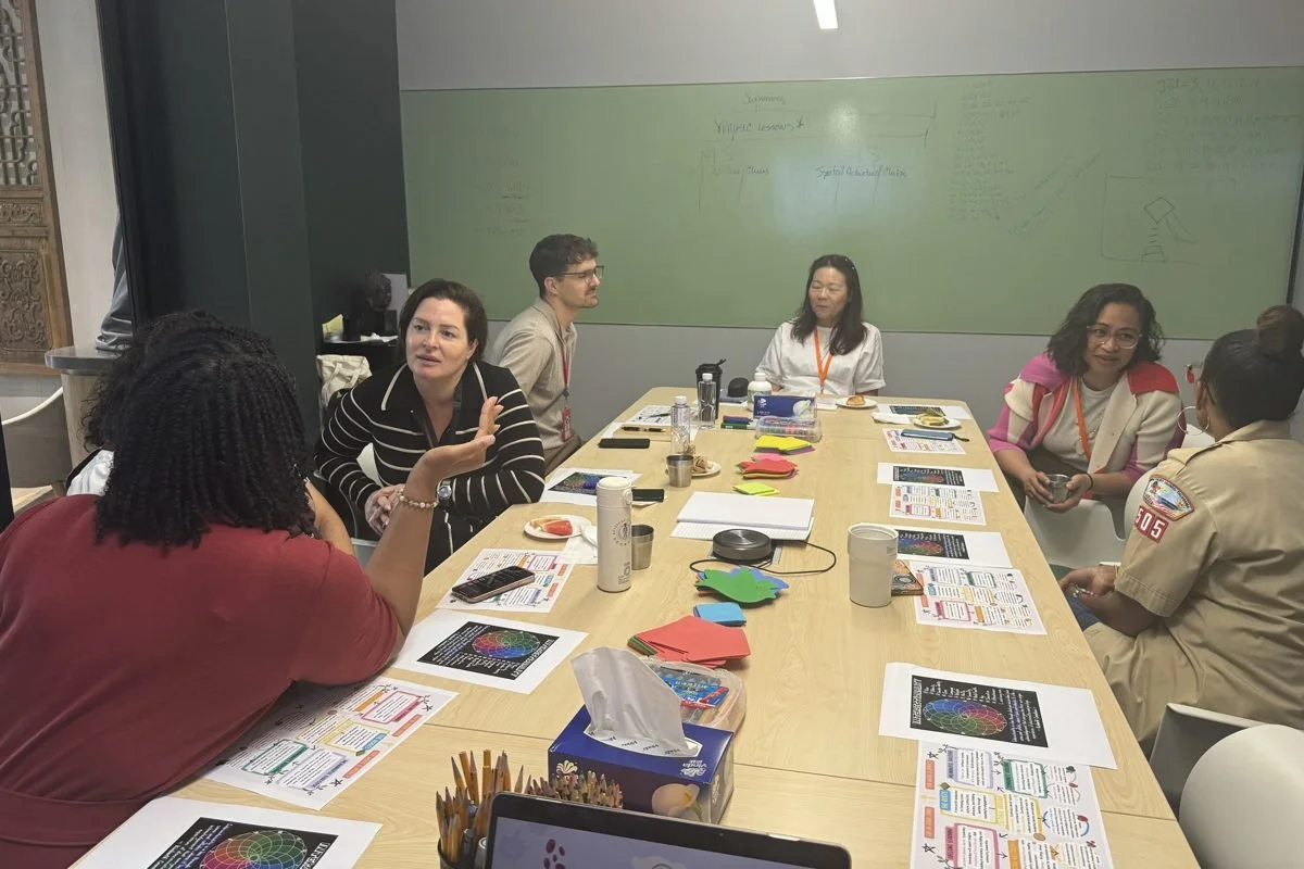 Teachers gathered around a long table with coffee and workshop cards