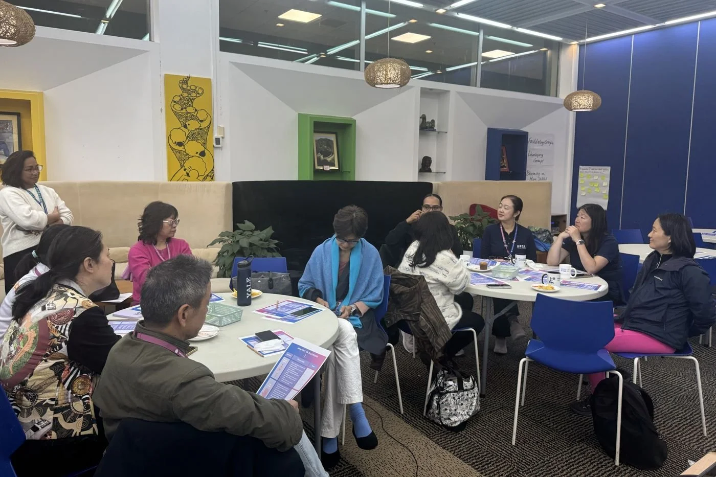 Parents in small-group dialogue at round tables during a cultural competence workshop