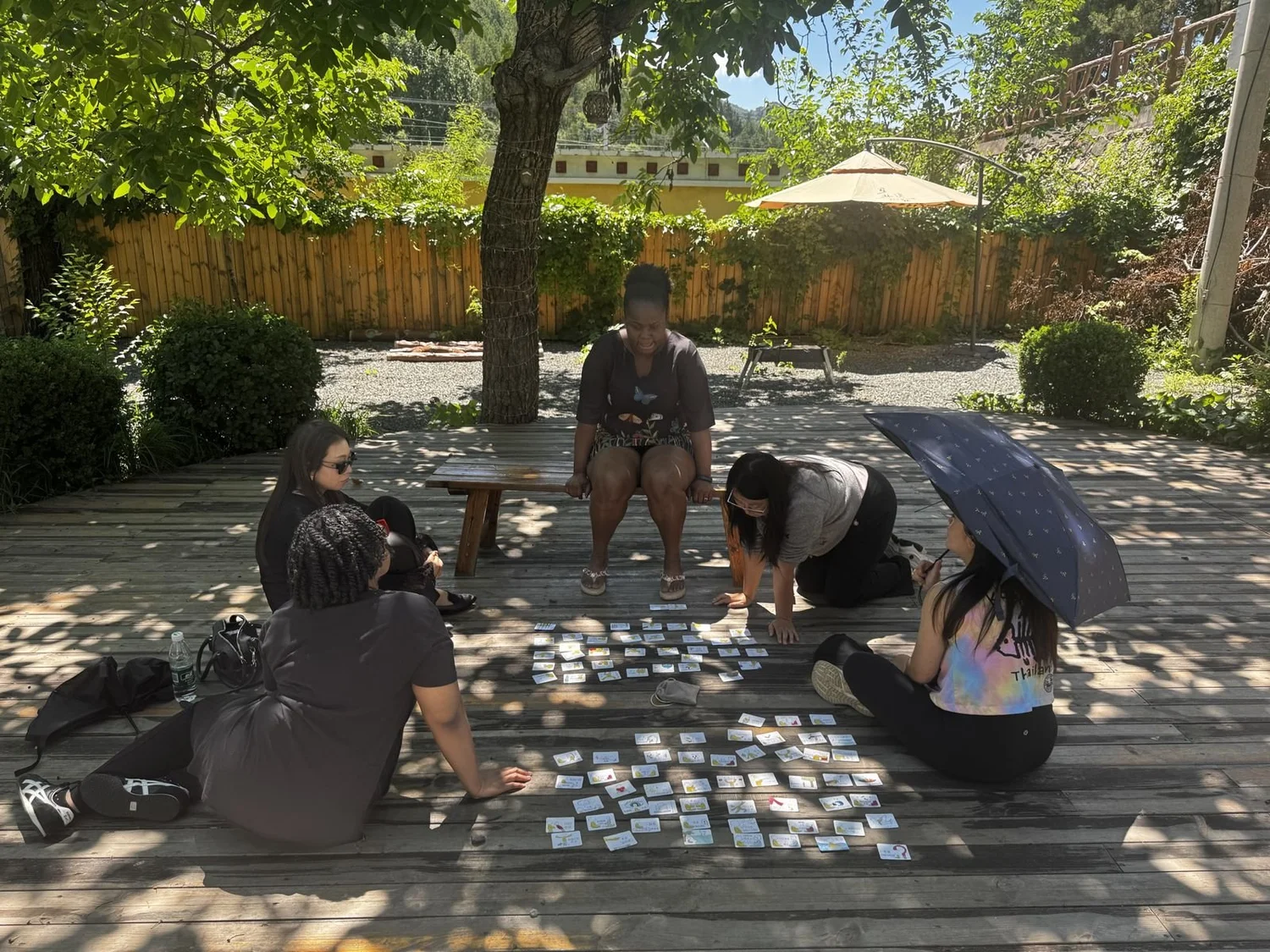 Retreat participants gathered under a tree in a sunlit garden