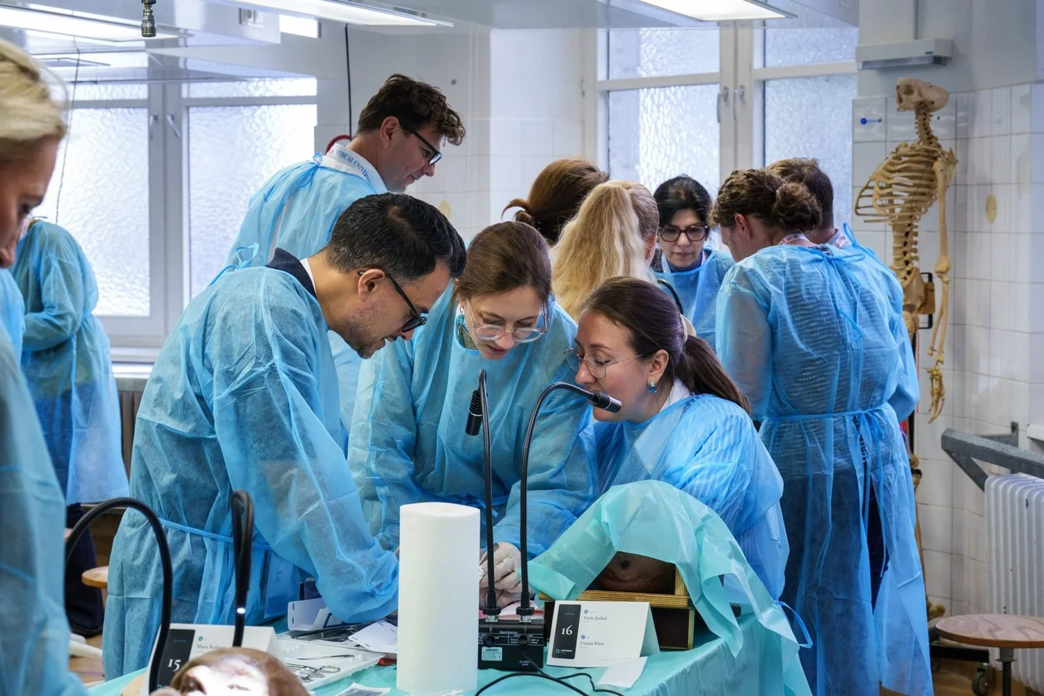 Participants and faculty gather around a training station during a wetlab