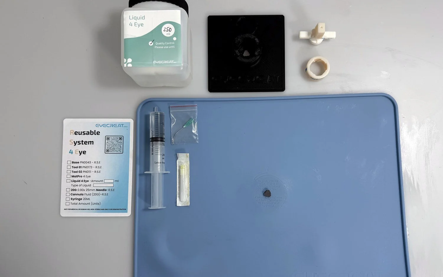 Contents of the R.S.E Kit next to a MatPro 4 Eye: assembly station, Tool 01, Tool 02, 20 ml syringe, fluid cannula, 20G needle, Liquid 4 Eye and checklist card