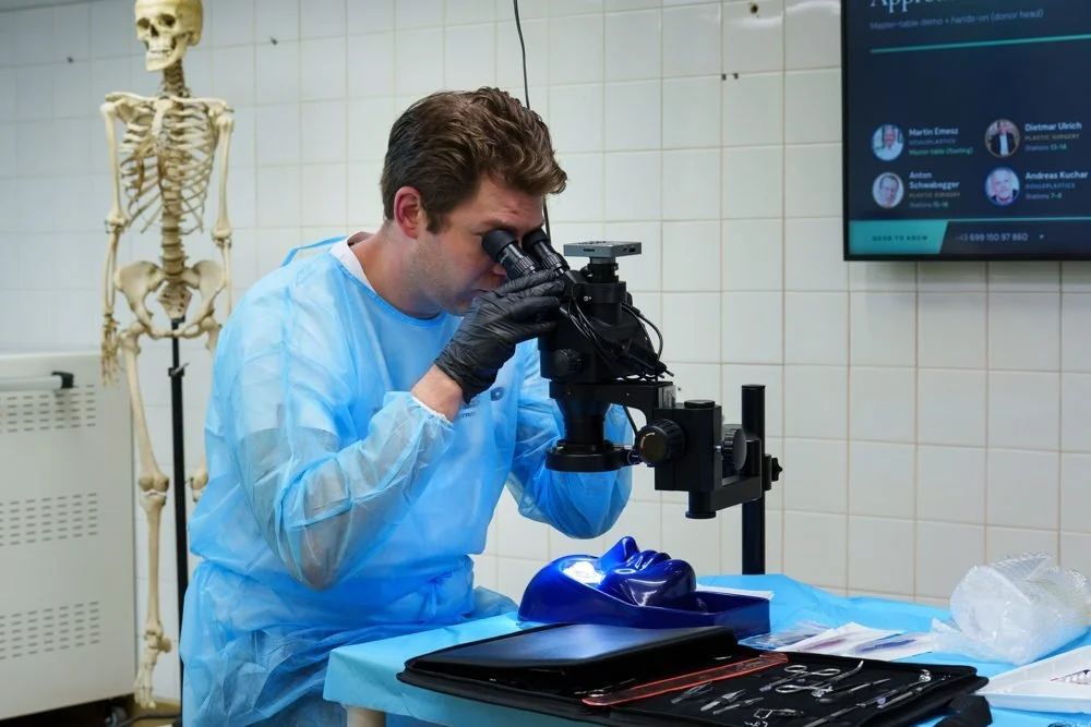 Participant working under a microscope at a wetlab station