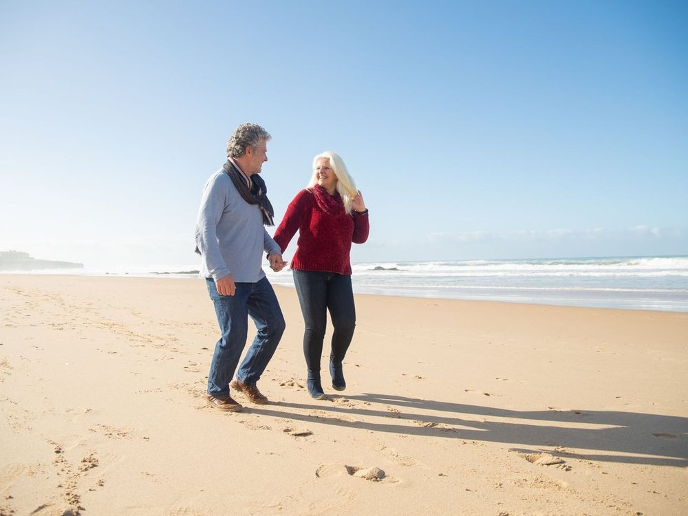 An older couple laughing on a walk along the beach