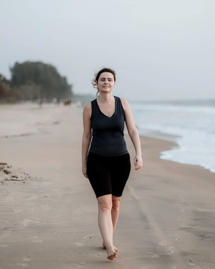 A woman walking barefoot along the shoreline