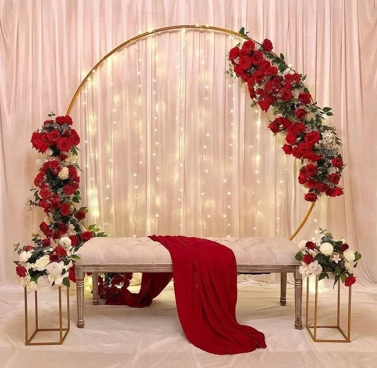 Gold circular arch with romantic red-and-white florals and soft draped lighting.