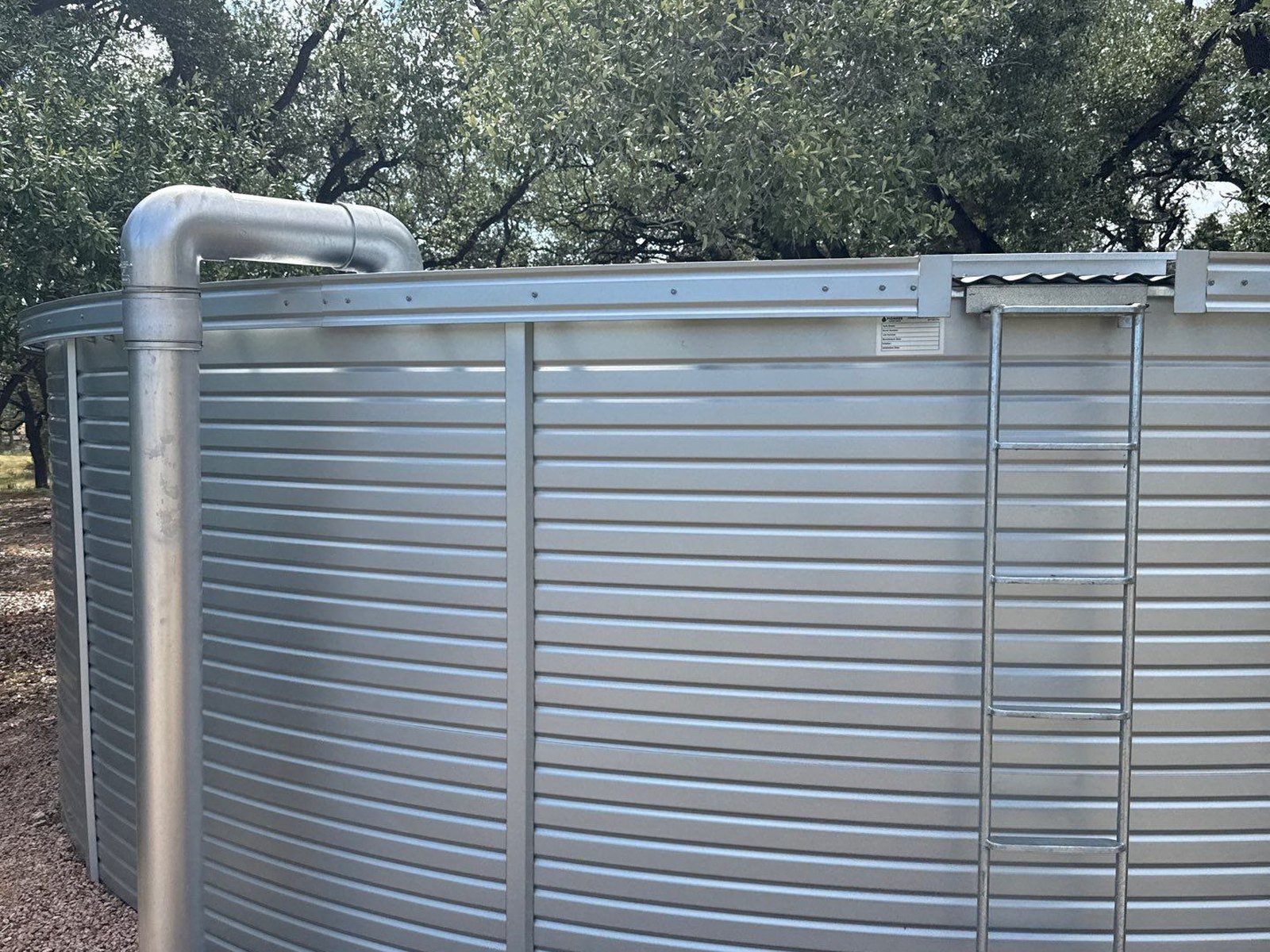 Candy cane inlet pipe carrying collected rainwater up and over into a galvanized storage tank