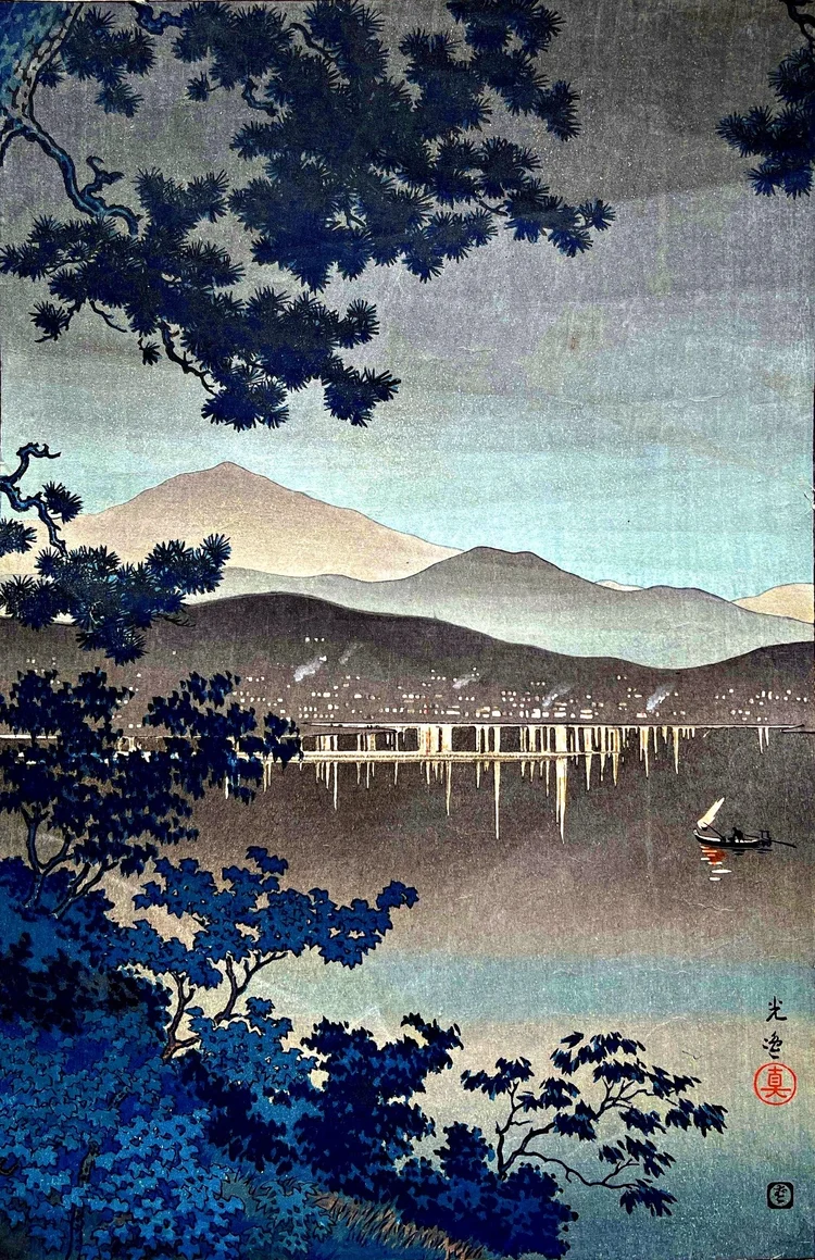 Canvas reprint of A Midnight Scene at Atami by Tsuchiya Koitsu: dark pine branches and foreground foliage frame a still bay, distant mountain ridges, waterfront lights and a small boat.