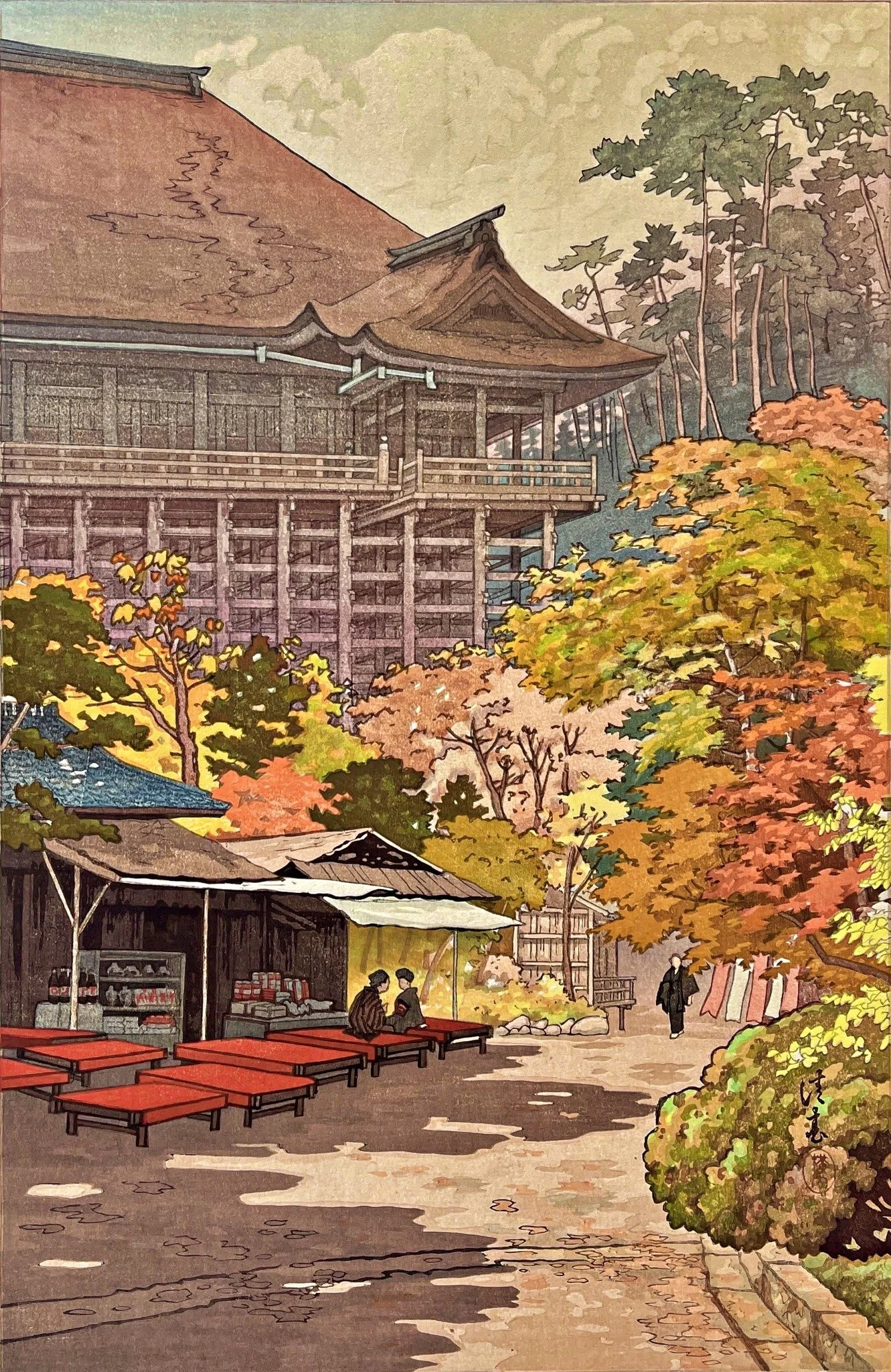 Maple Leaves at Kiyomizu Temple by Yokouchi Kiyoharu: Kyoto’s wooden temple hall and elevated platform above yellow, orange and red autumn foliage, a refreshment stall with red benches and two seated figures, and a person walking along a sunlit path.