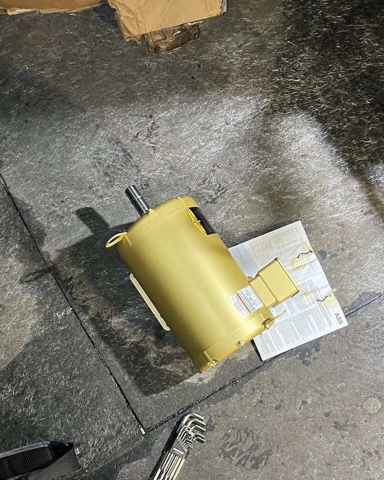 New yellow replacement motor on the rooftop next to its paperwork, ready to be installed