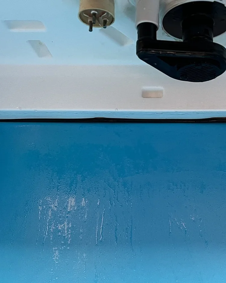 Underside of the ice machine evaporator section after cleaning: white surfaces and pump housing free of mold