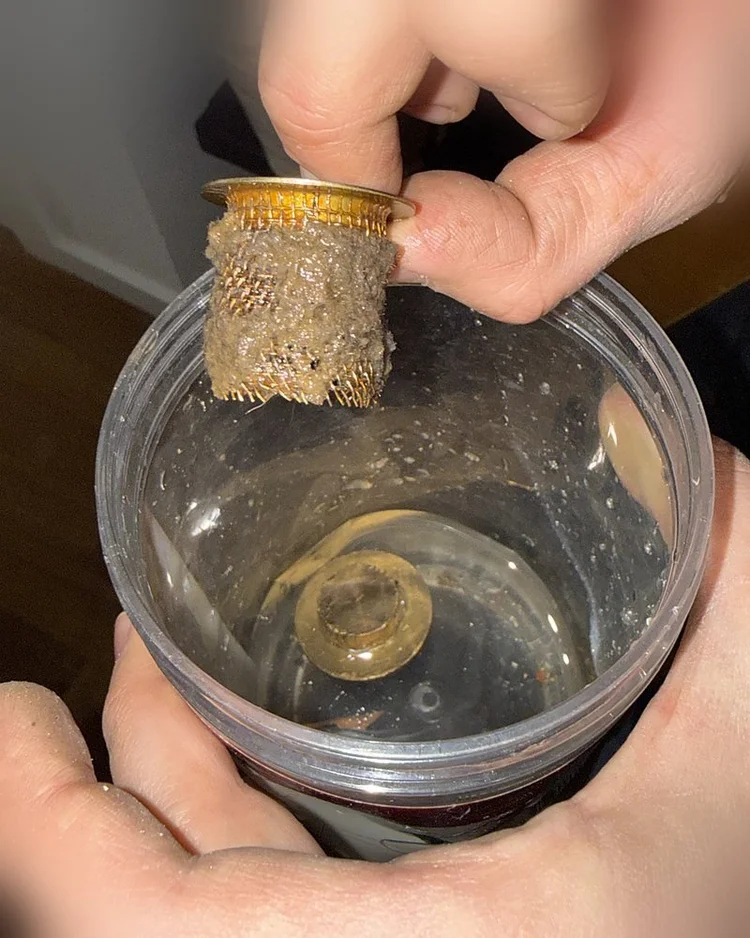 Strainer basket being cleaned in a clear container of water