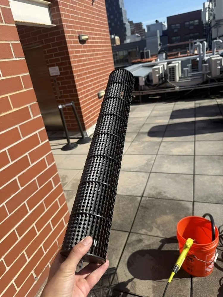 Cleaned ductless blower wheel held up on a Manhattan rooftop after pressure washing