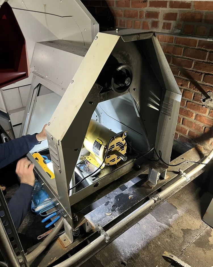 Technician working on the wiring of the new motor inside the exhaust fan housing