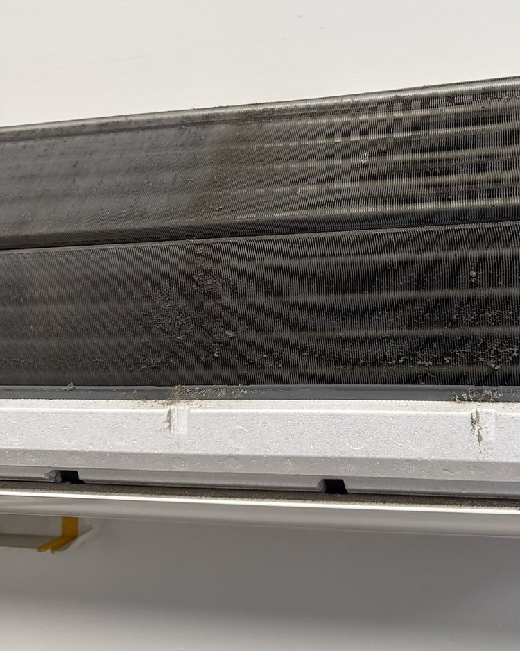 Ductless unit evaporator coil coated with gray grime before cleaning