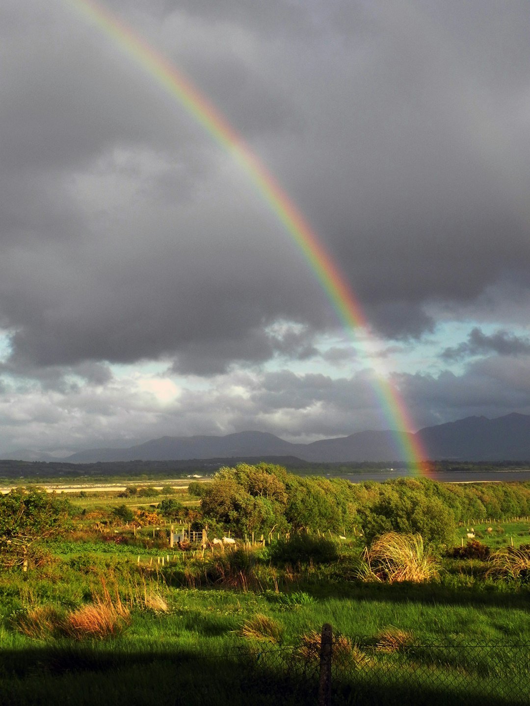 A rainbow over green Irish countryside beneath a changing sky