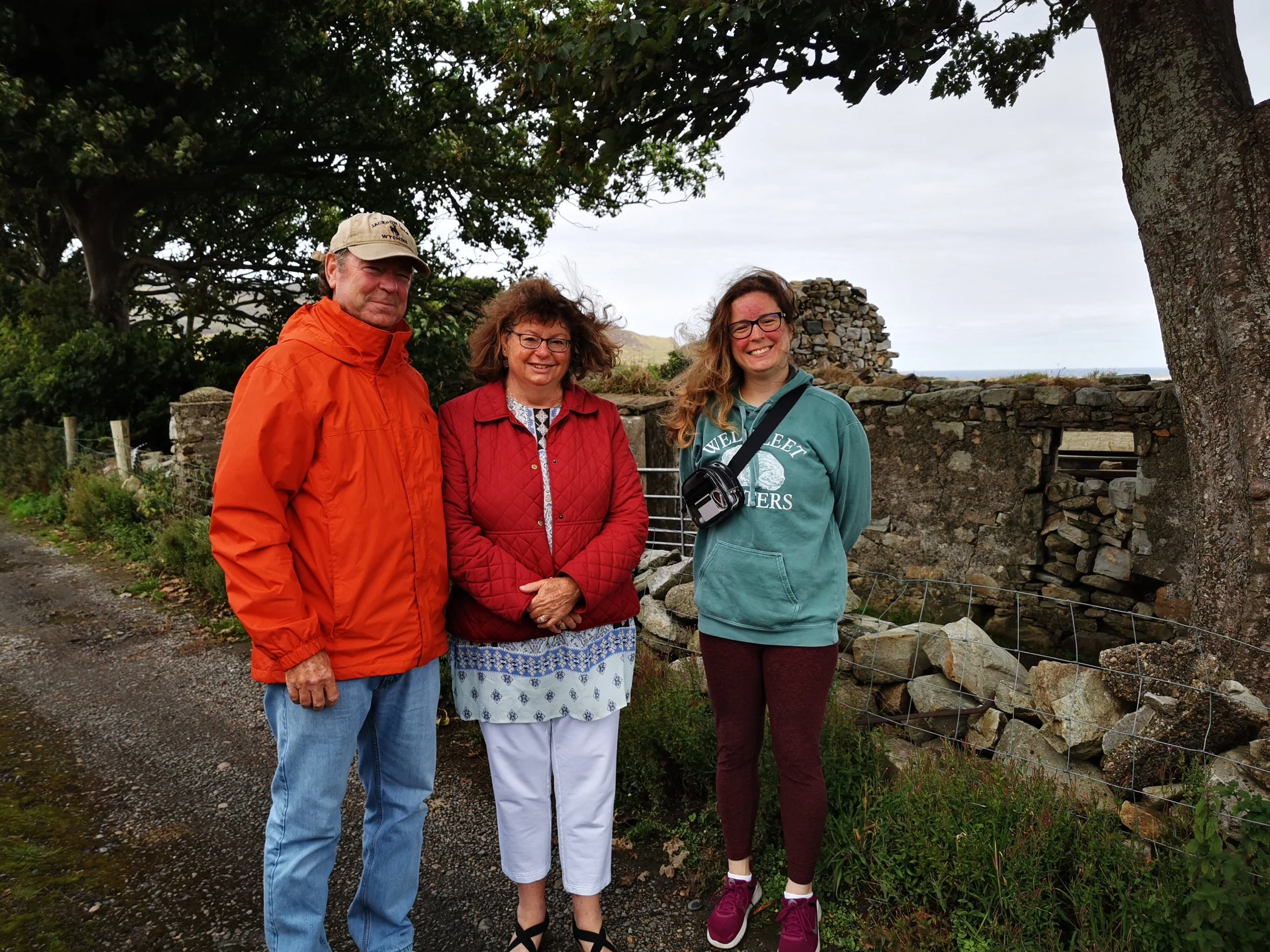Three visitors standing beside the stone walls of an old building