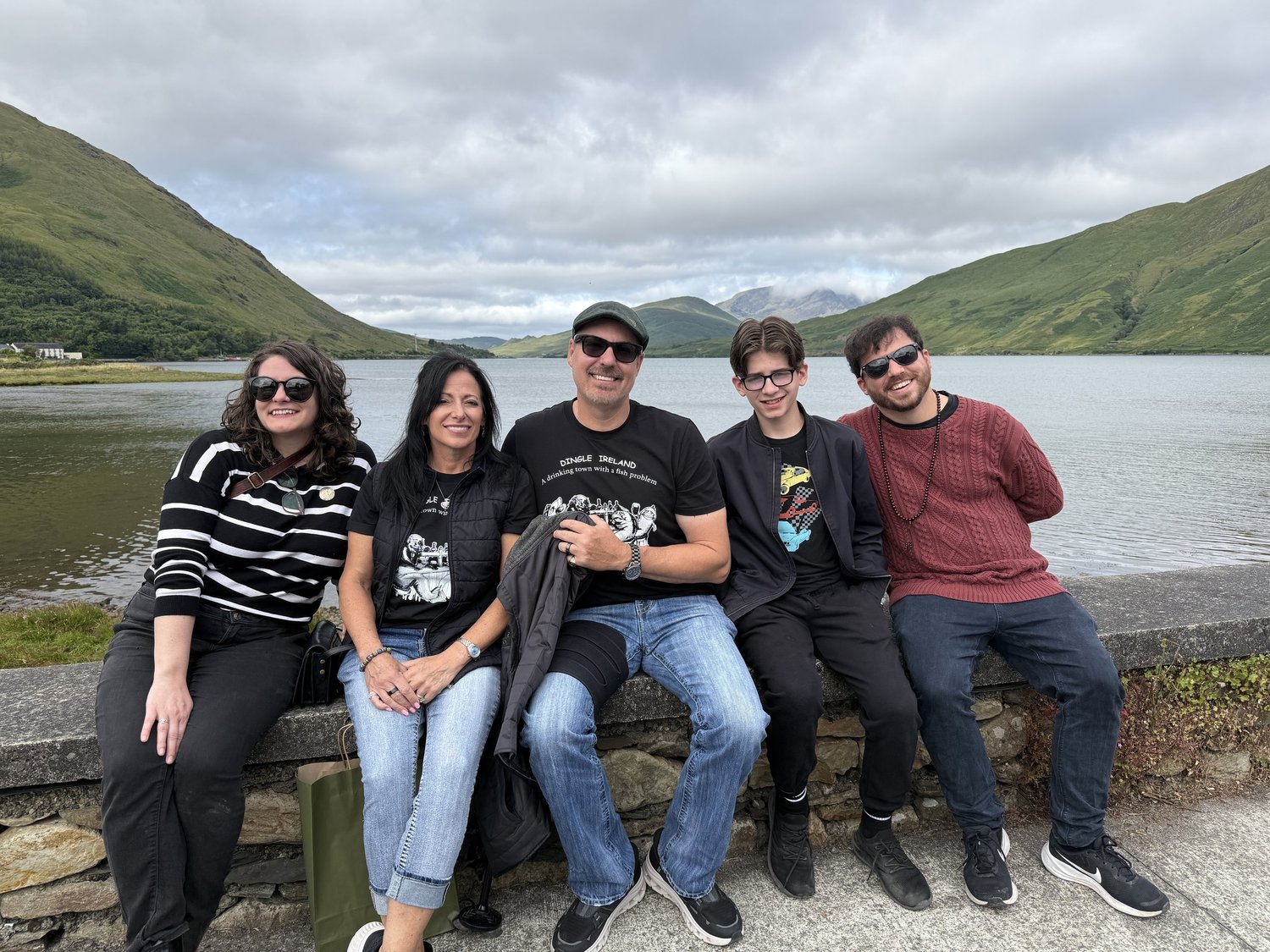 A tour group beside a lake surrounded by green mountains