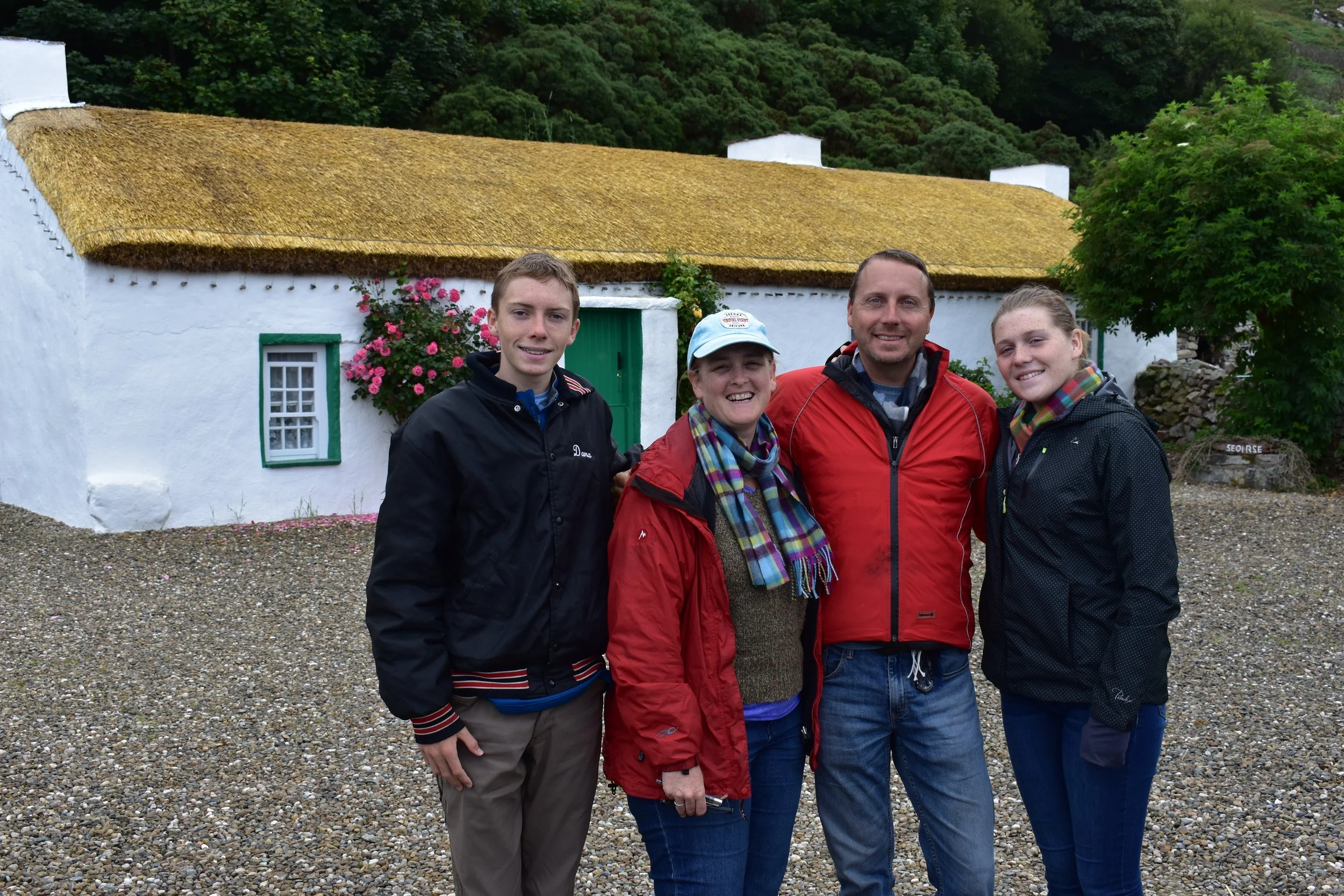 A family together in front of a traditional whitewashed thatched cottage