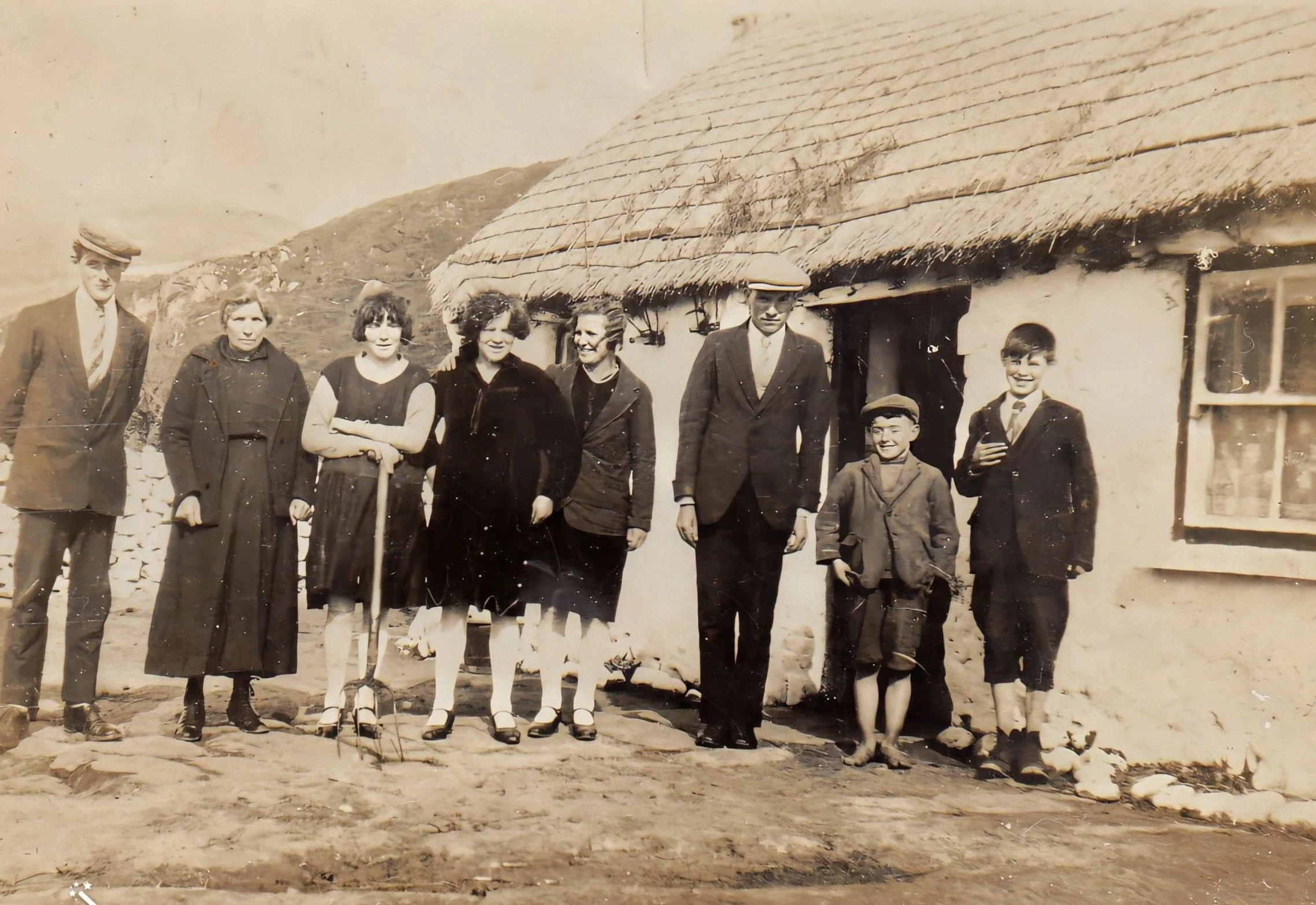 Historic family photograph outside a thatched cottage