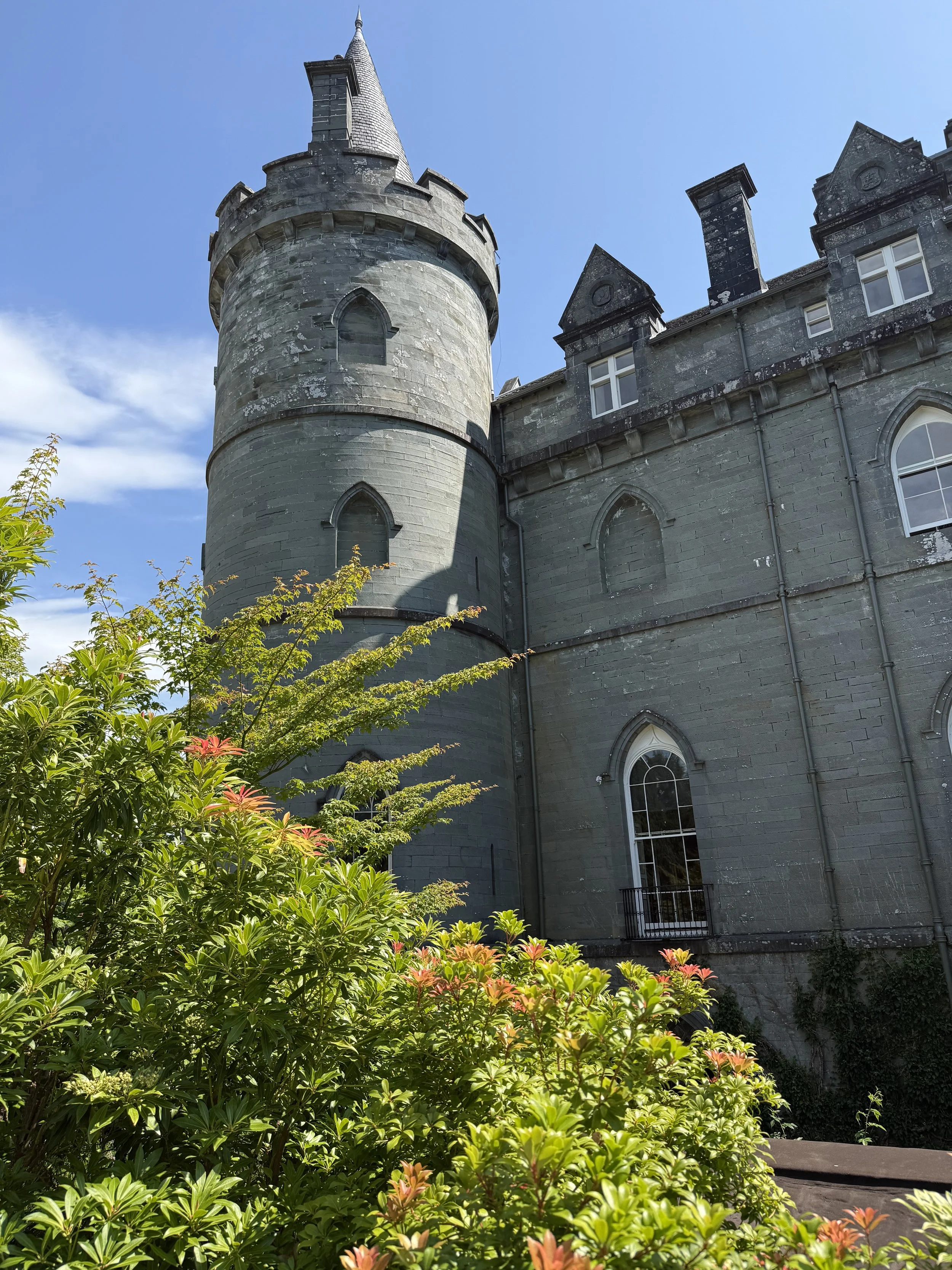 A Scottish castle turret rising above a leafy garden