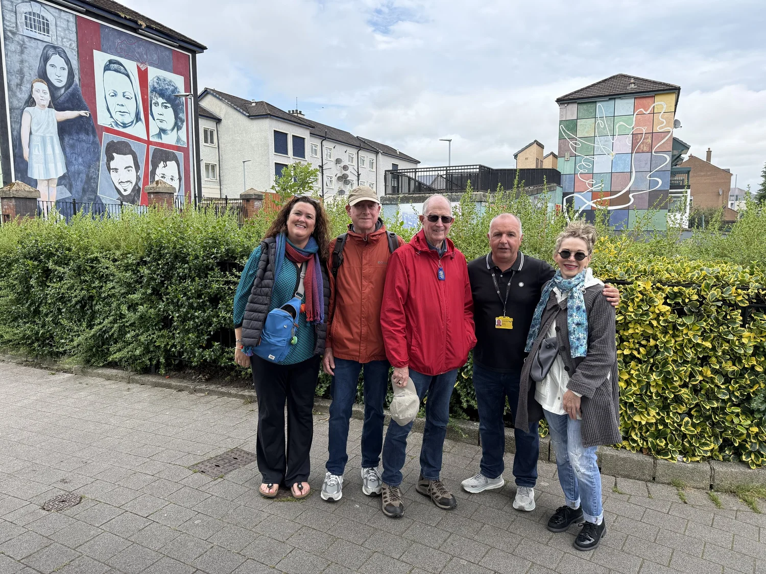 Jennifer and tour guests exploring Derry beside the Bogside murals