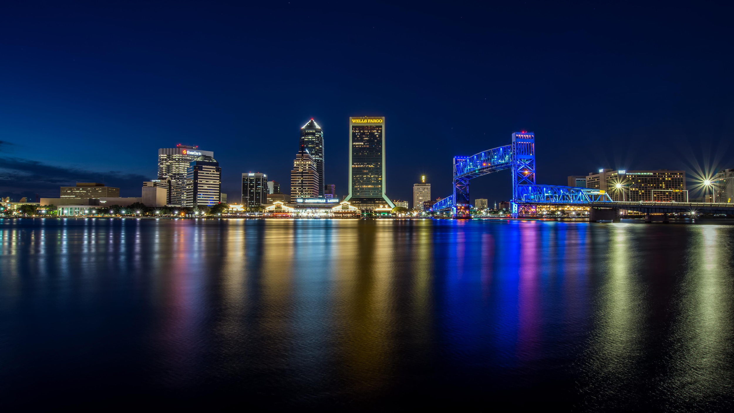 City skyline and illuminated bridge reflected in the water at night