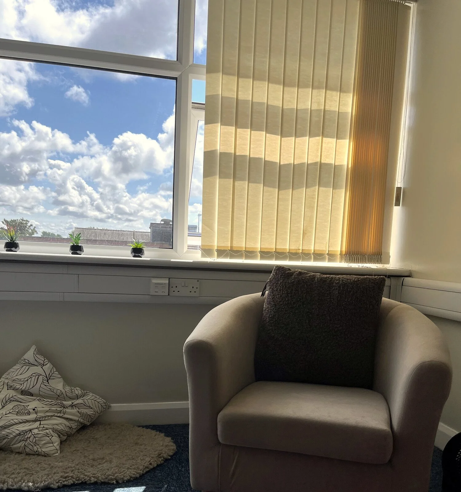 Angela’s counselling room in Bispham, with a big window, blue sky and a cosy armchair