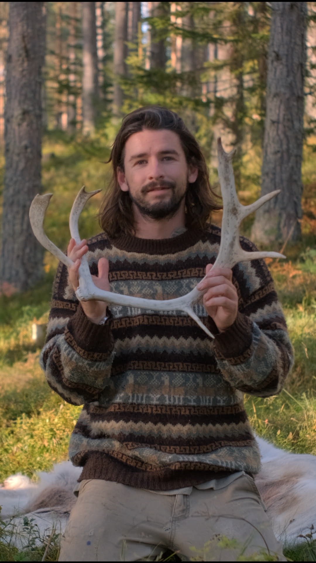 George in a pine forest, holding a reindeer antler