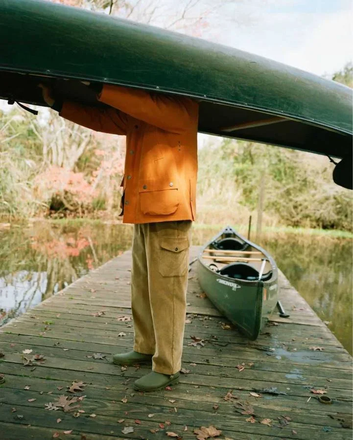 Man carrying a green canoe on a jetty