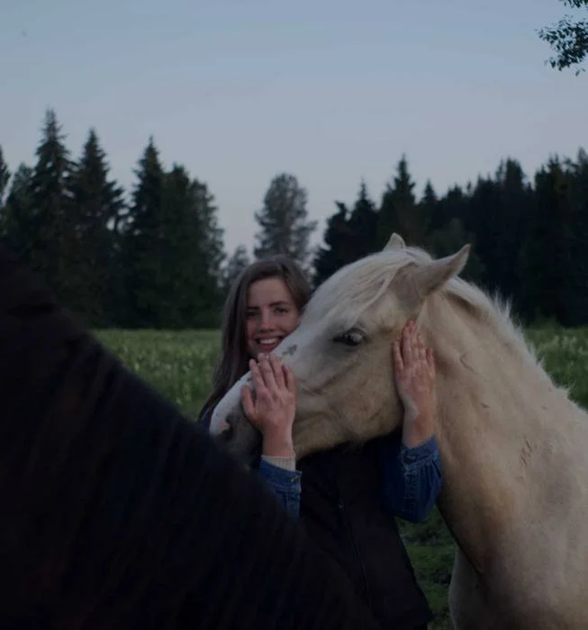 Guest resting her face against a white horse